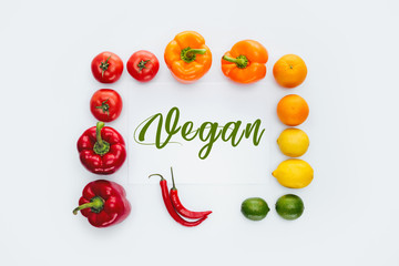 Fototapeta premium top view of frame of vegetables and fruits with word Vegan isolated on white