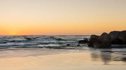 Fototapeta na wymiar Cape Town sunset on a sandy beach with reflections on the water