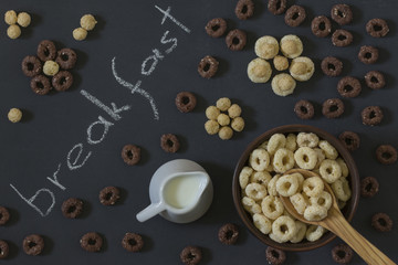 Obraz na płótnie Canvas Bowl of Whole Grain Cereal rings with milk on a background of a black chalkboard.