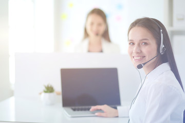 Smiling businesswoman or helpline operator with headset and computer at office