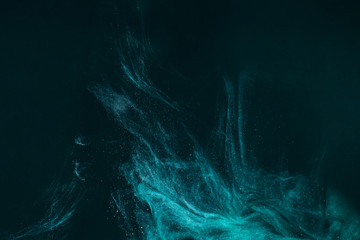 abstract artistic background with turquoise paint flowing on black