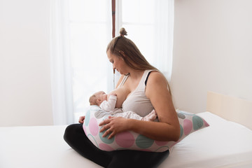 Obraz na płótnie Canvas mother breastfeeding baby girl in white interior
