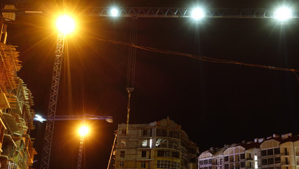 Construction site at night, working tower cranes.