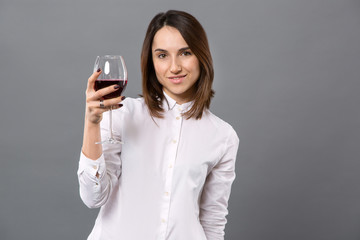 To you. Beautiful cheerful woman raising a glass of wine while saying a toast