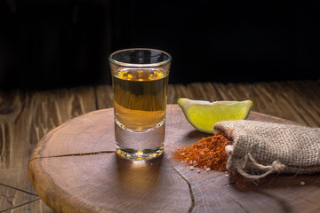 Mezcal - traditional Mexican strong alcoholic drink with lime slices and worm salt on a old wooden board.