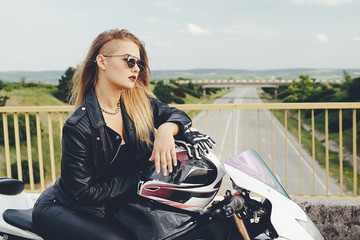 Fototapeta na wymiar Beautiful woman posing with sunglasses on a motorbike