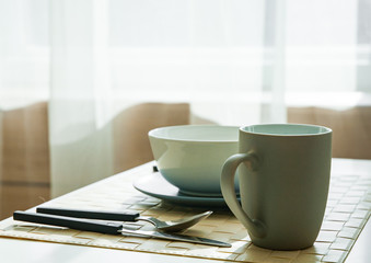 Wooden table with cup and dish in modern dinning room at home.