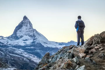 Selbstklebende Fototapete Bergsteigen Junger Mann beim Bergsteigen in den Schweizer Alpen mit Matterhorn im Hintergrund