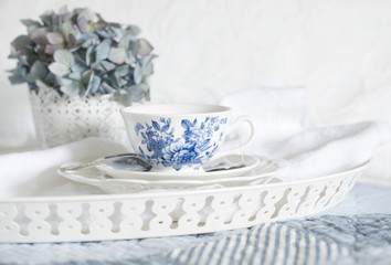 Fototapeta na wymiar Vintage style photograph of a blue and white teacup on a white tray on the bed