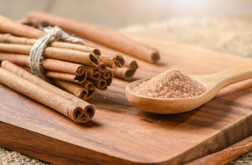 sugar on wood scoop and cinnamon sticks