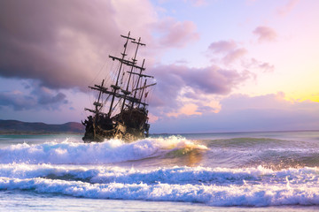Pirate ship at the open sea at the sunset