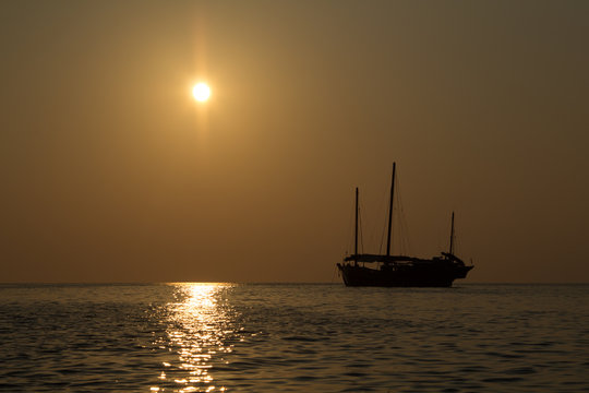 Wooden junk sail boat in the setting sails in the sunset of the Andaman Sea in Thailand