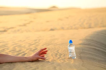  Hand try to catch the bottle of water on sand desert in hot temperature. Concept of to die of thirst. © cegli