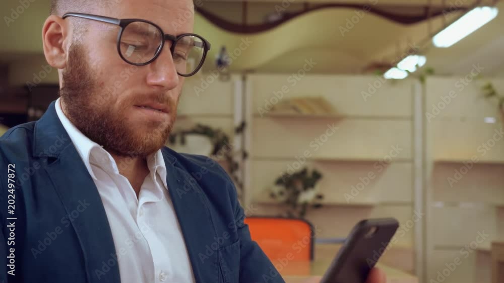 Poster handsome man using smartphone texting message indoors. caucasian businessman with beard messaging on
