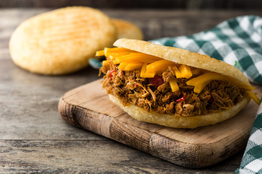 Arepa with shredded beef and cheese on wooden background. Venezuelan typical food

