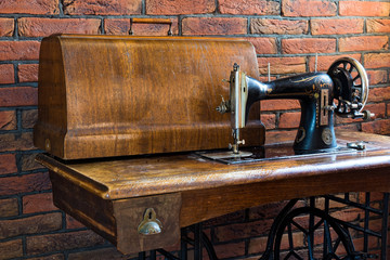 Old sewing machine with its wooden table near a wall of red bricks in Greece.