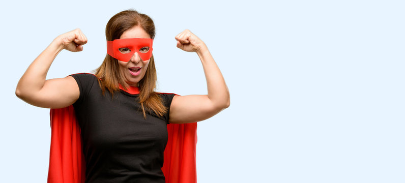 Middle age super hero woman wearing red mask and cape happy and excited celebrating victory expressing big success, power, energy and positive emotions. Joyful isolated blue background