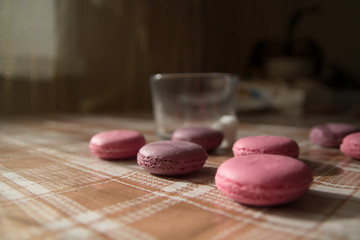Obraz na płótnie Canvas pink and lilac macarons with a glass on the background