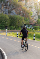 Naklejka premium A man is on the bicycle on the road near the hill