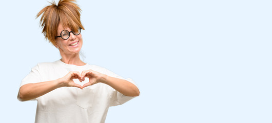 Obraz premium Crazy middle age woman wearing silly glasses happy showing love with hands in heart shape expressing healthy and marriage symbol isolated blue background
