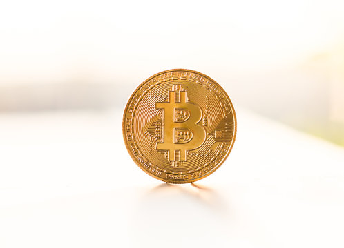 Gold bitcoin coin placed on white background in the light of sunset. Virtual currency symbol
