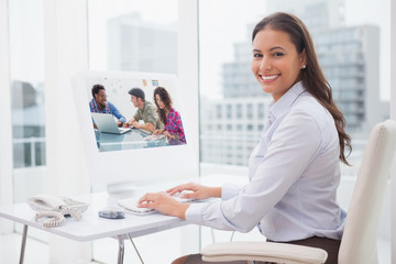 Creative team working together against smiling businesswoman working at her desk