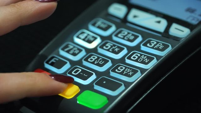 Shop assistant inserting a credit card into a pos and inserting pin-code of the card