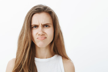 Definitely no. Portrait of gloomy displeased childish girlfriend with blond hair, frowning and frimacing from disgust or displeasure, expressing disappointment and bad mood over gray background