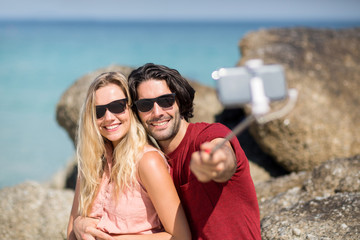 Couple taking selfie with monopod at beach