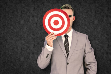 Businessman holding target against grey background