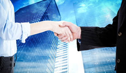 Close up of a business people closing a deal  against low angle view of skyscrapers