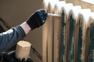 worker paints the metal water heating radiator