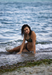 Fototapeta na wymiar Beautiful girl in waves on the beach