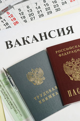 Calendar and Russian documents for employment: work book, passport and insurance certificate on paper with the inscription in Russian Vacancy