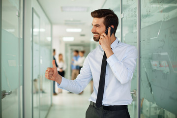 Young businessman on the phone with a group of people behind out of focus