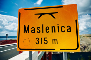 Maslenica bridge. Dark yellow plate with the name of the bridge and its length given in meters.