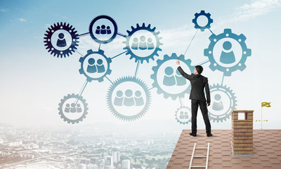 Businessman on house roof presenting teamwork and connection concept. Mixed media