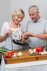 Happy mature couple preparing food together in kitchen