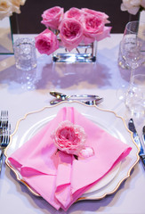 Beautiful table setting with a white tablecloth and pink napkins. Red cutlery, beautiful dining utensils. Wedding Decor Textiles