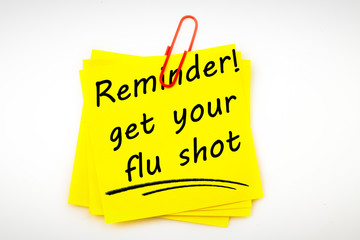 Flu shot reminder against sticky note with red paperclip
