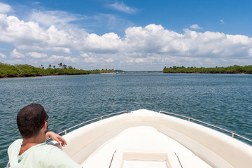 Man in boat looking at island in the sea of Bahia, Brazil.