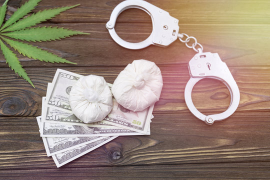 drugs, hemp. dollars, handcuffs on a wooden background. illegal sale of drugs
