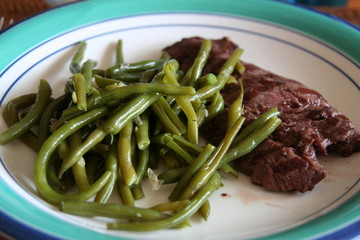 Boiled french bean and beef steak surved on the withe with green plate