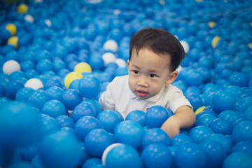 Fototapeta na wymiar A happy boy is playing plastic balls.