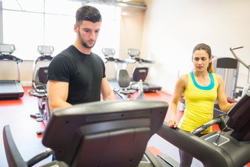 Fototapeta na wymiar Couple using treadmills together