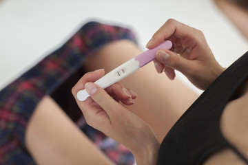 Woman holding in hands pregnancy test. She is expecting a baby.