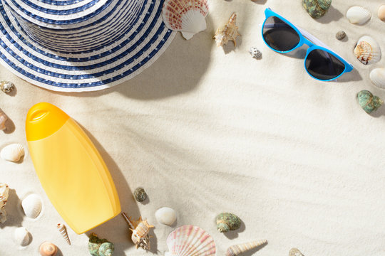 Beach Hat, Sunglasses, And Sunscreen Are Among The Seashells On The Sand