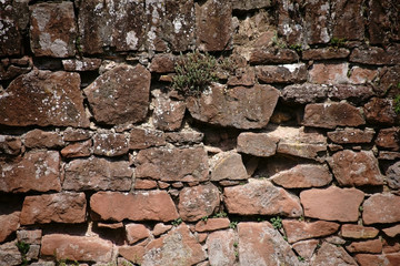 Rustikale Mauer Nahaufnahme / Eine rustikale Mauer aus versetzten und abgebrochenen Steinen mit vereinzelten sukkulenten Pflanzen in den Mauerritzen.