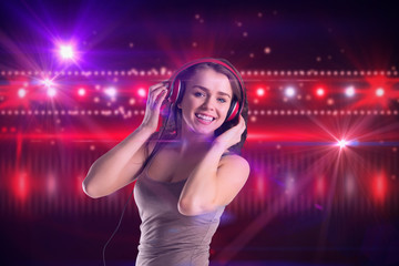 Pretty girl listening to music against digitally generated nightlife light design