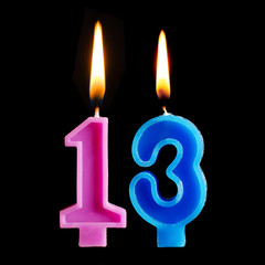 Burning birthday candles in the form of 13 thirteen figures for cake isolated on black background.